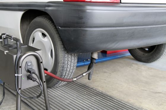 Voiture branchée à un banc d'essai de châssis dans un garage, avec un câble relié à la roue arrière.