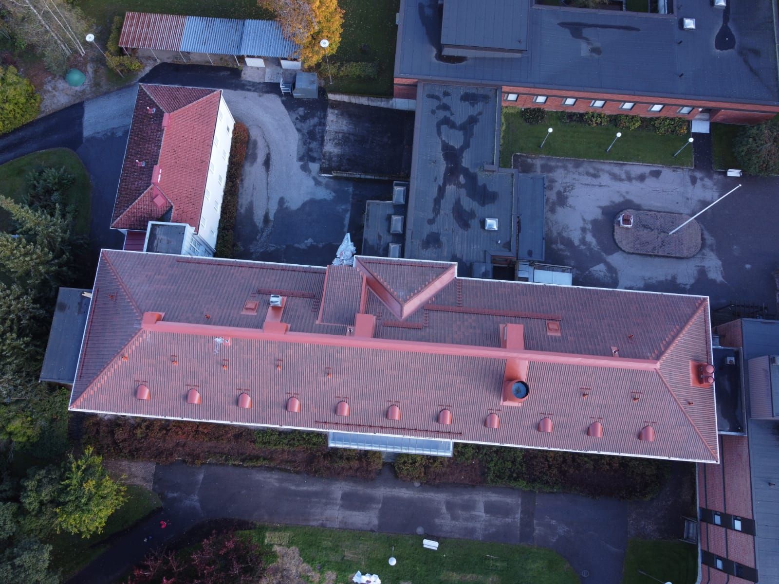Ilmakuva punakattoisesta rakennuskompleksista sisäpihoineen ja ympäröivän vehreyden kanssa