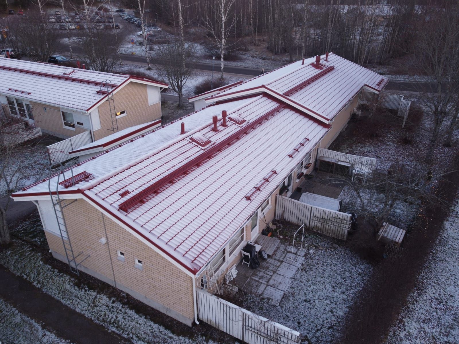Lumipölyn peittämiä asuinrakennusten kattoja ja pihoja hiljaisella alueella ylhäältä katsottuna.