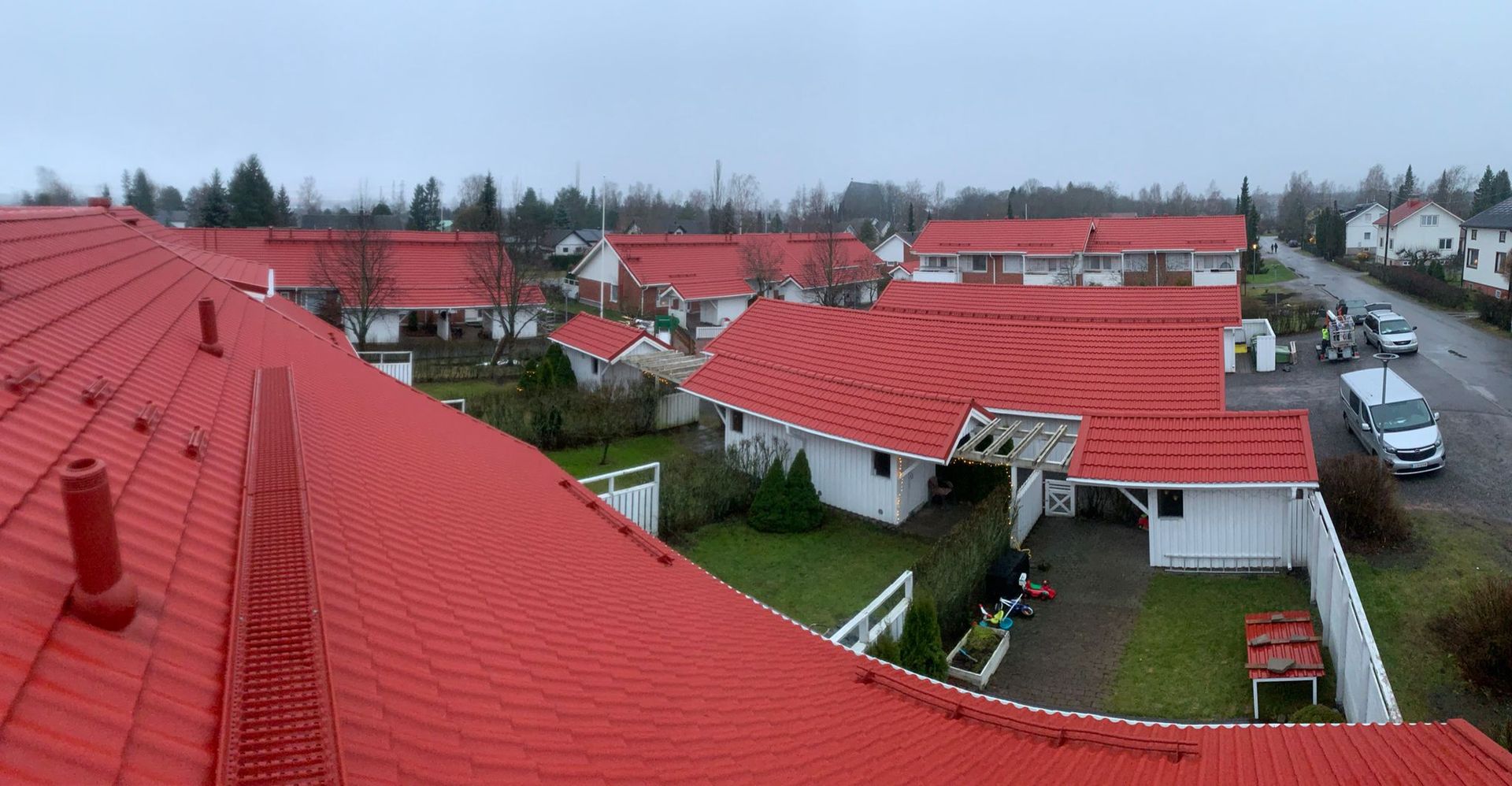 Punakattoisia taloja asuinalueella pilvisen taivaan alla ylhäältä katsottuna.
