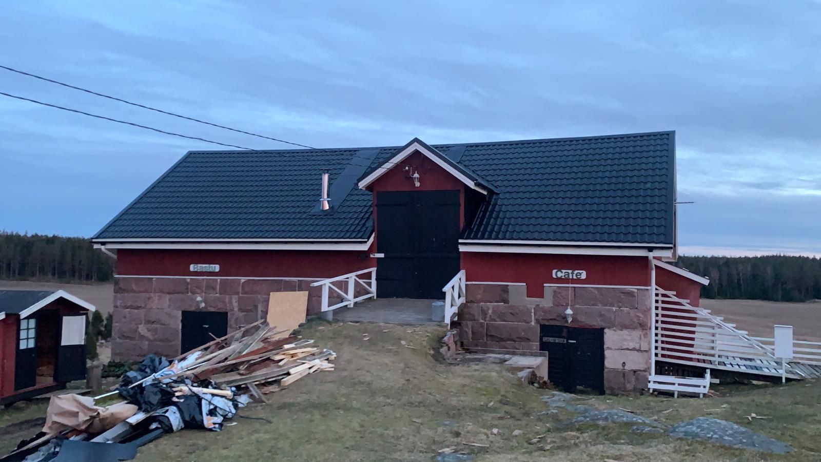 Punainen lato, jossa on tumma katto ja valkoiset reunukset, jota ympäröivät romukasat maaseudun pellolla.