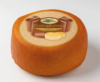 Rueda de queso Terra Montes con corteza marrón y logotipo en la parte superior.
