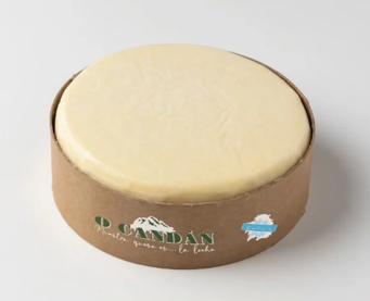 Queso redondo en envase de cartón. Queso amarillo claro con la marca 