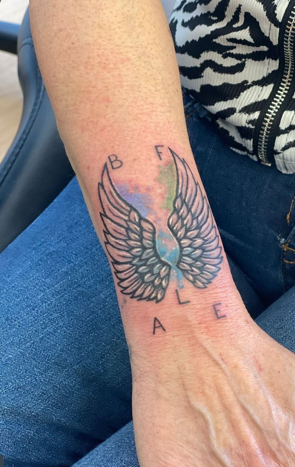Una mujer tiene un tatuaje de alas en su muñeca.