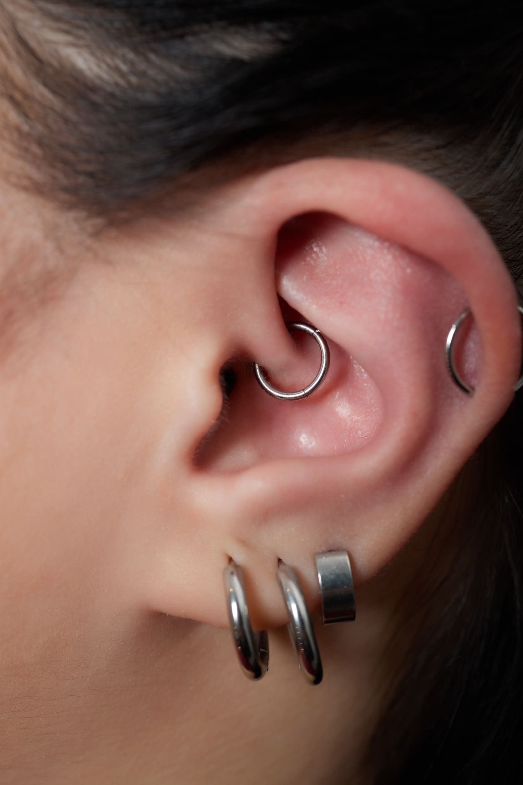 Un primer plano de la oreja de una mujer con múltiples perforaciones.