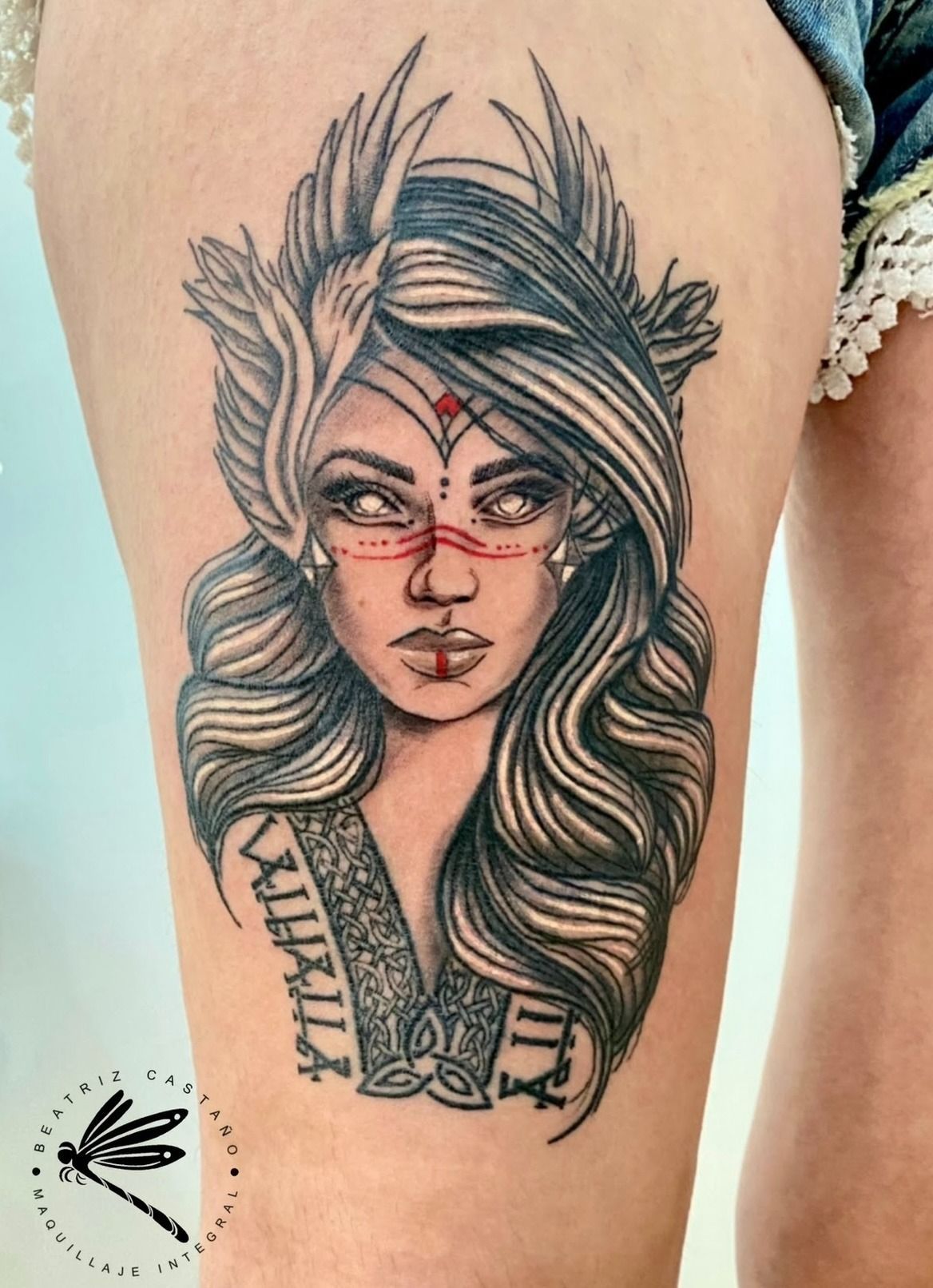 Una mujer tiene un tatuaje de la cara de una mujer en el muslo.