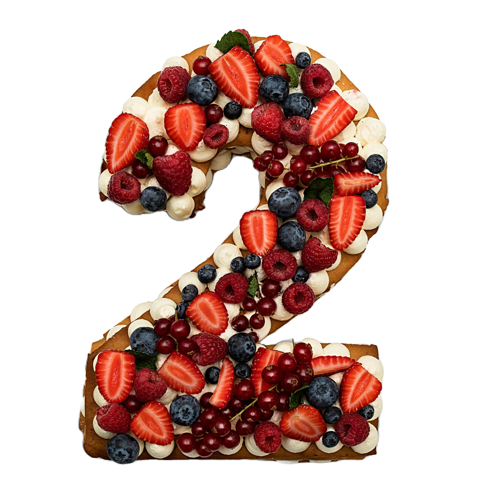 Un gâteau en forme de 2 garni de fraises, de myrtilles, de framboises, de groseilles et de quenelles de crème.