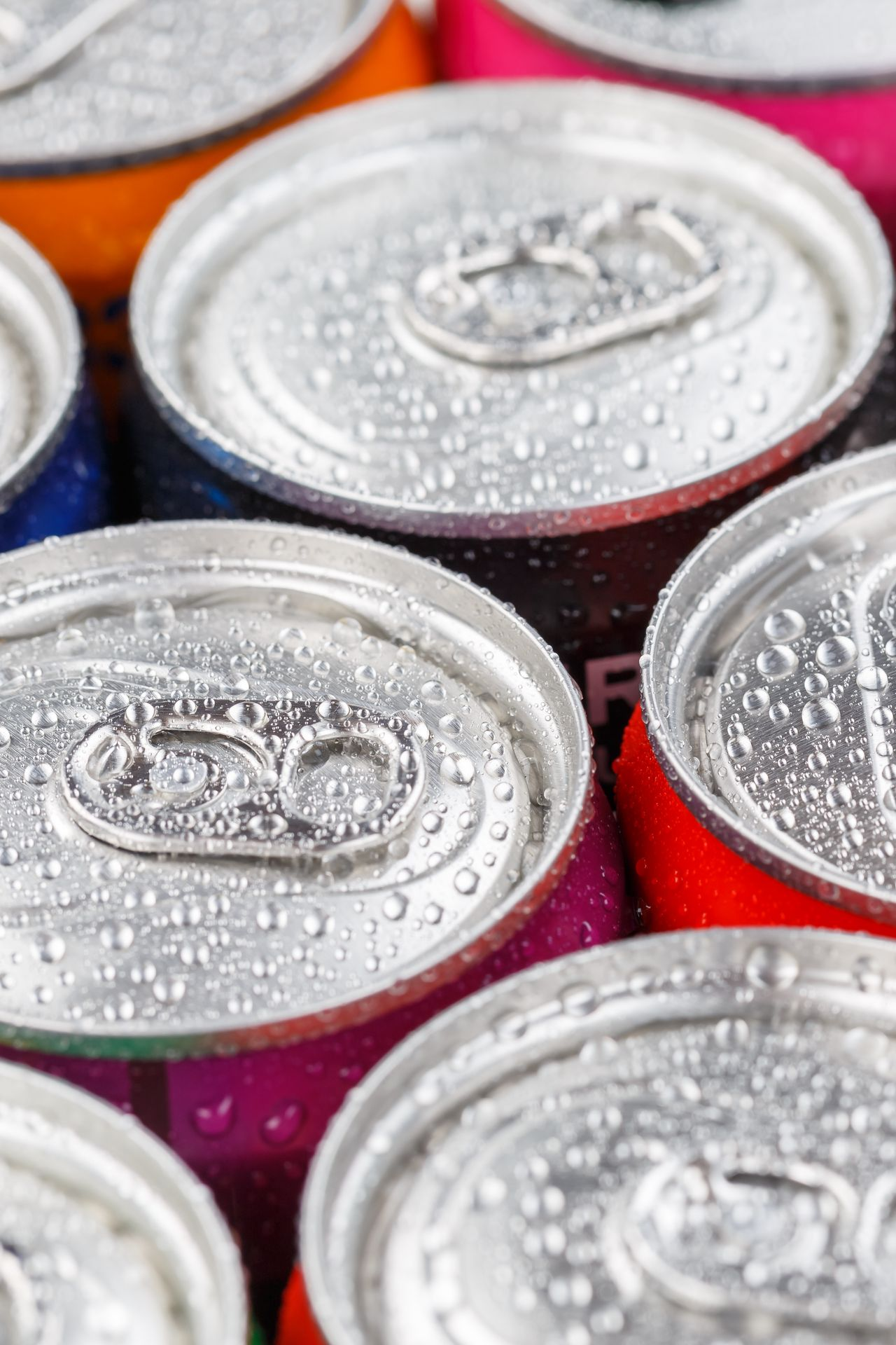 Canettes de soda colorées, couvertes de condensation, vues de dessus, faisant ressortir leurs languettes métalliques.