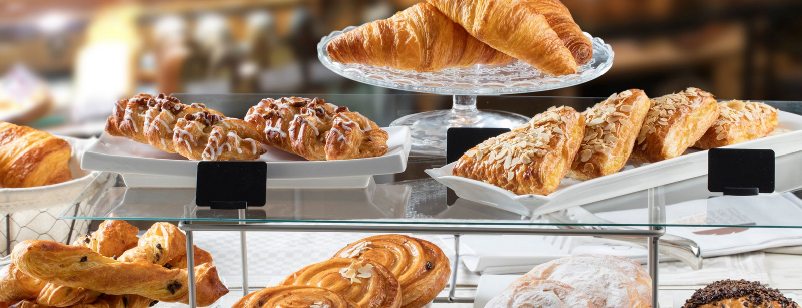 Une vitrine remplie d'un assortiment de viennoiseries dorées, notamment des croissants, des viennoiseries et des scones.