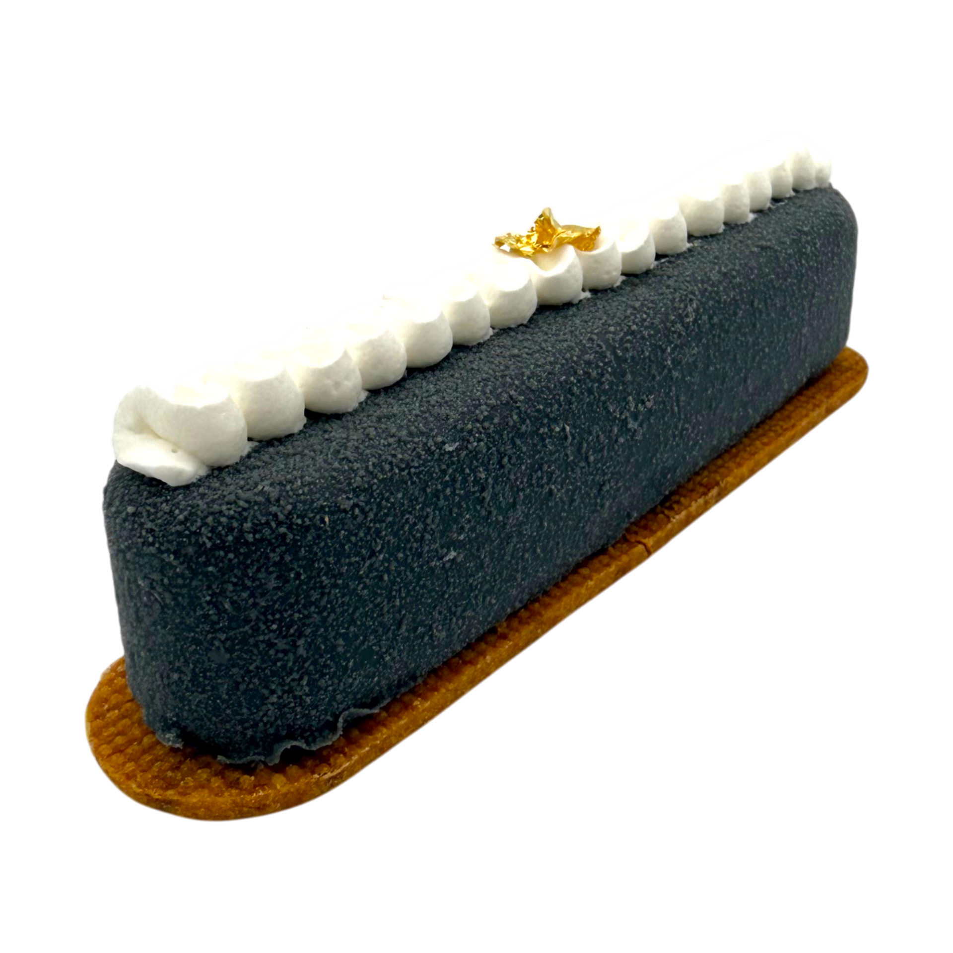 Une longue bûche de dessert, gris foncé à la texture veloutée, repose sur une fine base brun doré, recouverte de crème blanche et de feuilles d'or.