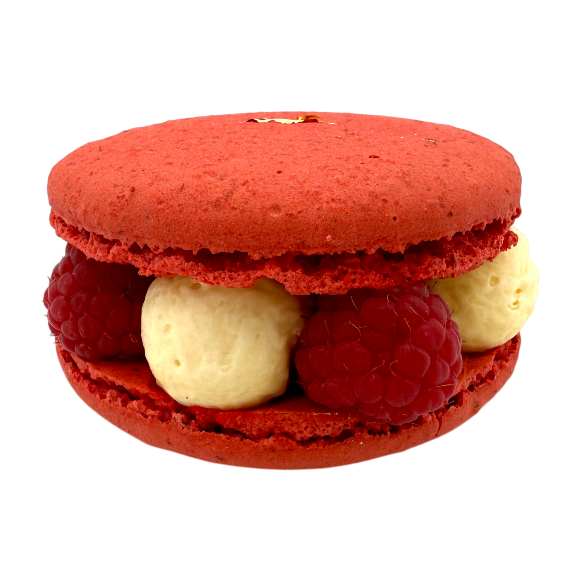 Un macaron à la framboise rouge, fourré de crème et garni de framboises fraîches entre deux coques de meringue rouge vif.