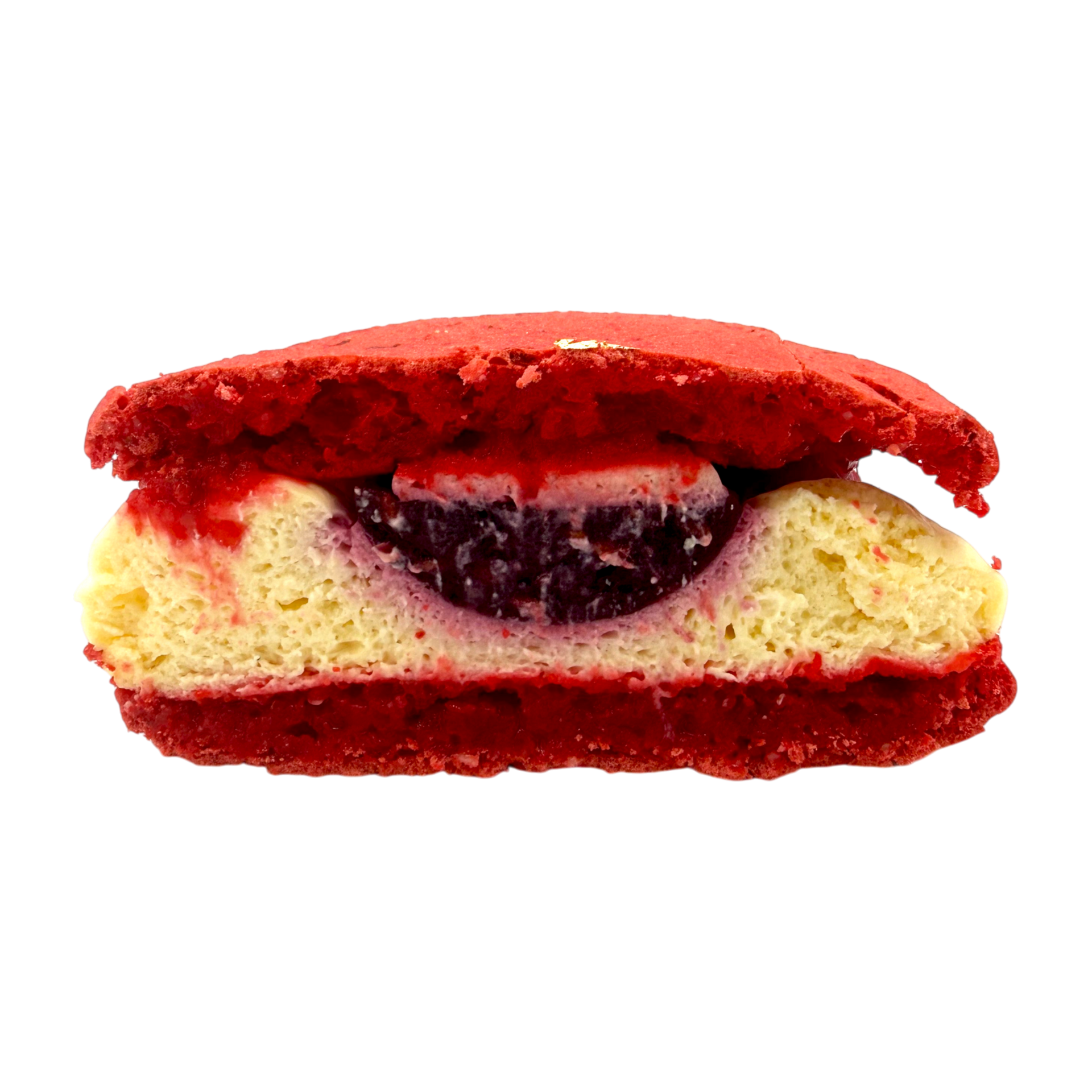 Un macaron rouge fourré d'une crème claire et d'un cœur de confiture de fruits rouge foncé, sur fond blanc.