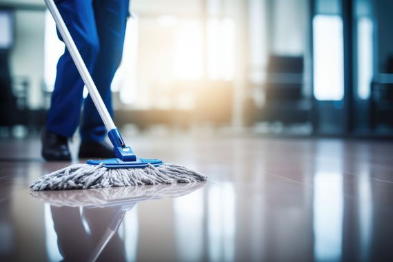 Drei Kollegen räumen ein Büro aus, indem sie Elektronikgeräte und persönliche Gegenstände in Kartons verstauen und Möbel mit Plastikfolie abdecken.