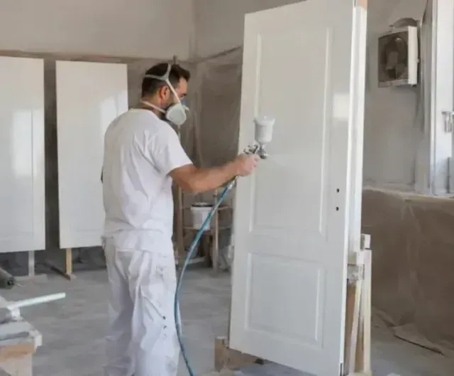 Un pintor laca una puerta blanca 