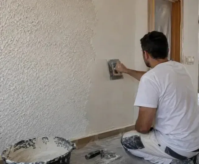 Profesional retirando gotelé de una pared interior