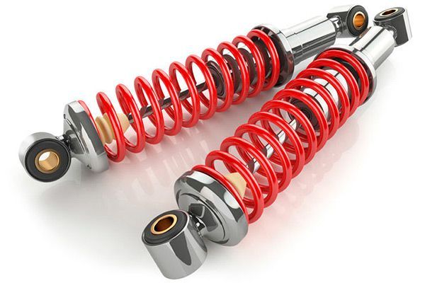 Dos amortiguadores con resortes helicoidales de color rojo sobre un fondo blanco.