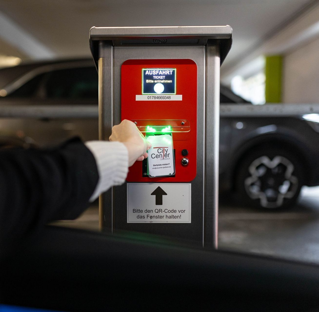 Dauerparker zeigt sein Ticket am QR-Code Scanner einer Ausfahrtssäule um die Schranke zu öffnen