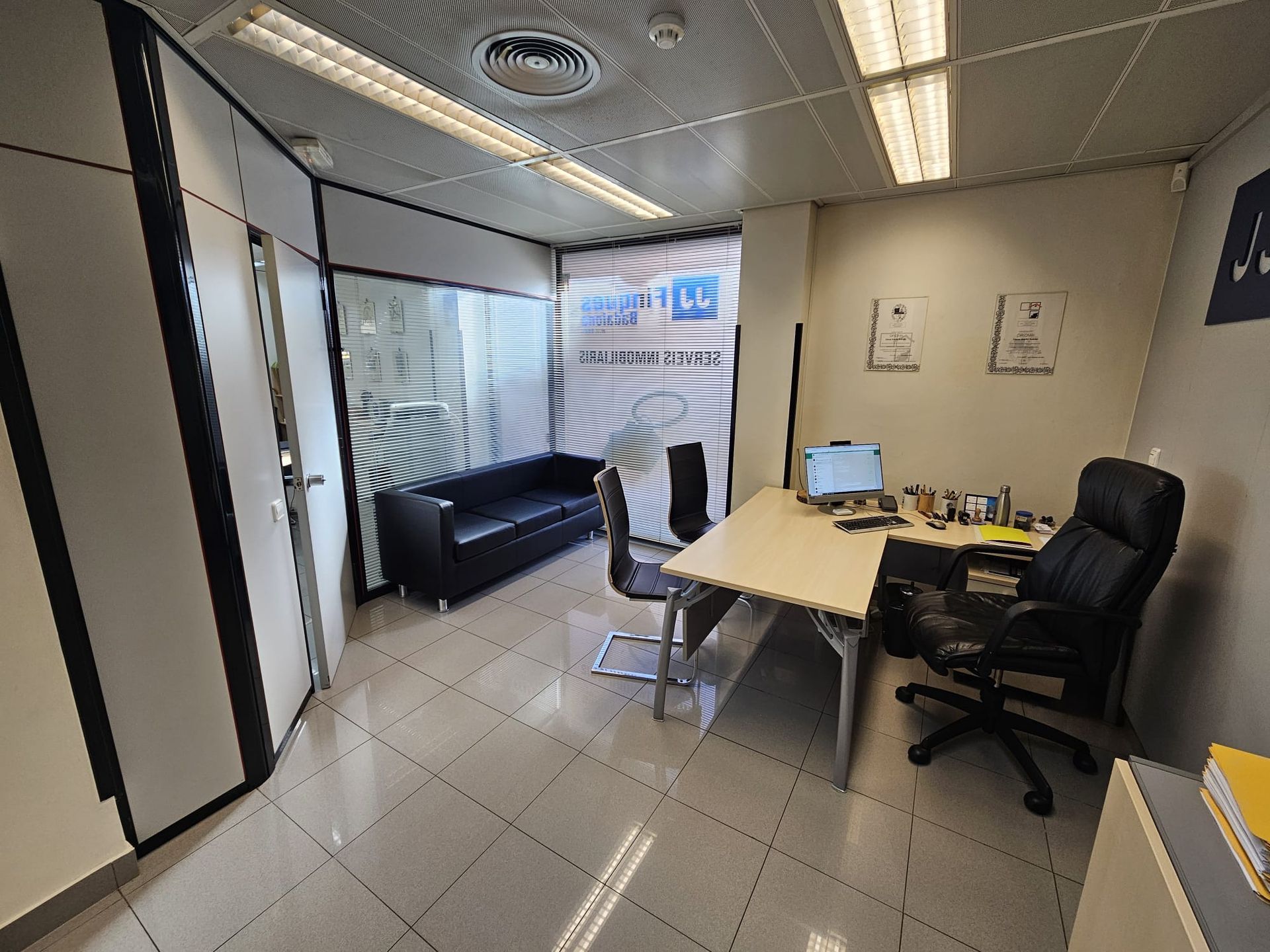 Una habitación con un sofá y un escritorio con una computadora encima.