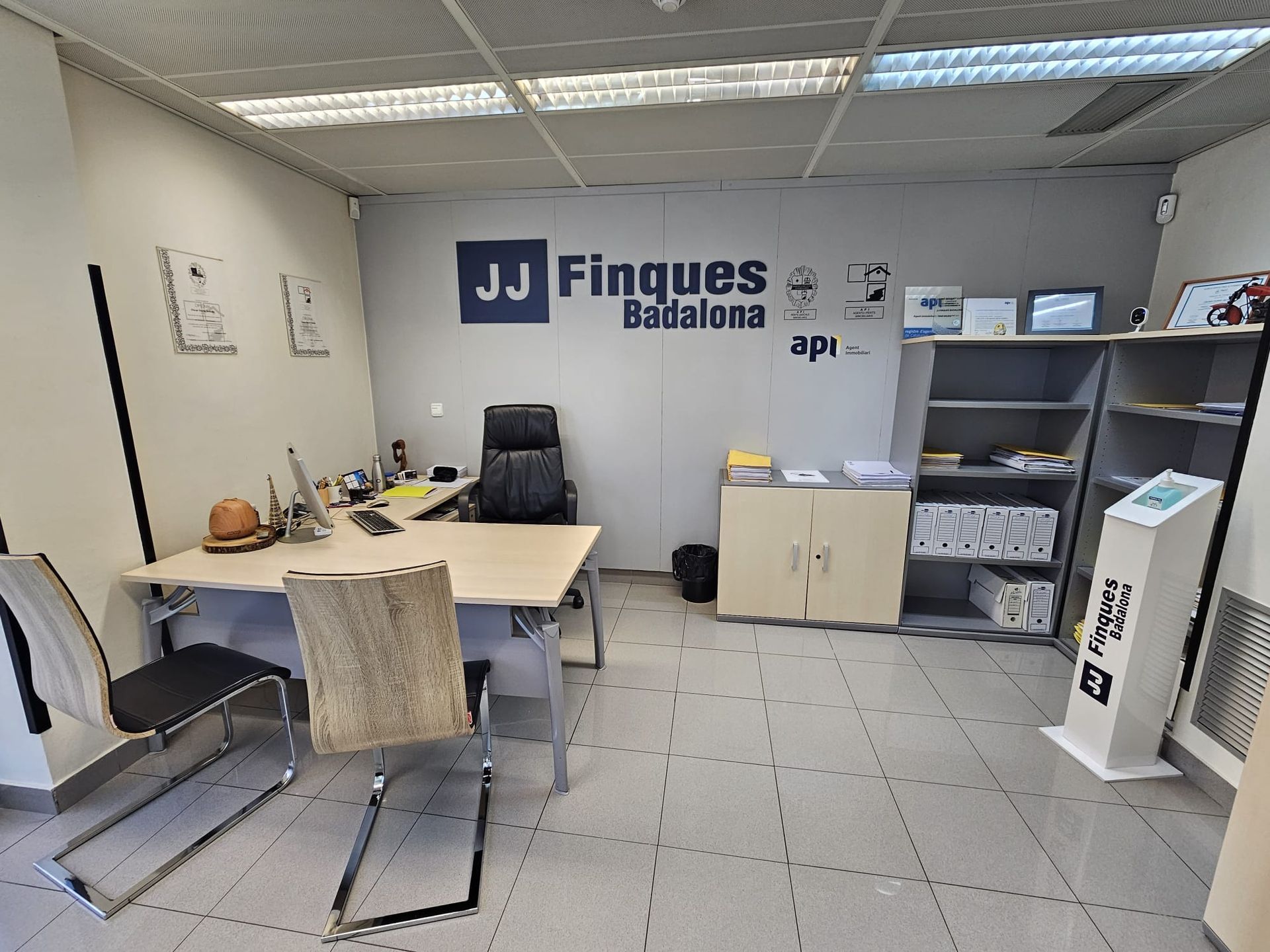 Una habitación con un escritorio y sillas y un cartel que dice jj finques