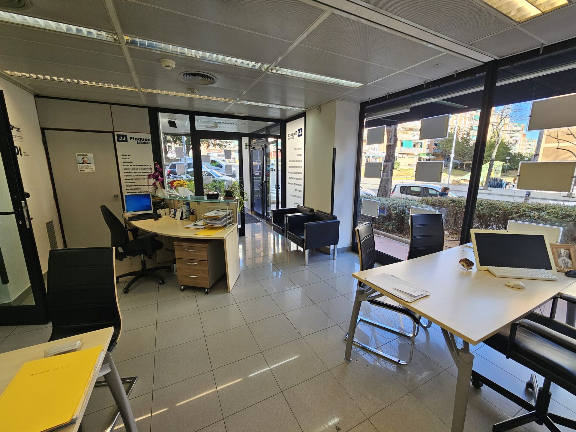 Una oficina grande con muchas ventanas, mesas y sillas.