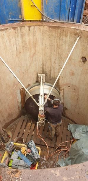 Ein Mann arbeitet an einer Maschine in einem Loch im Boden.