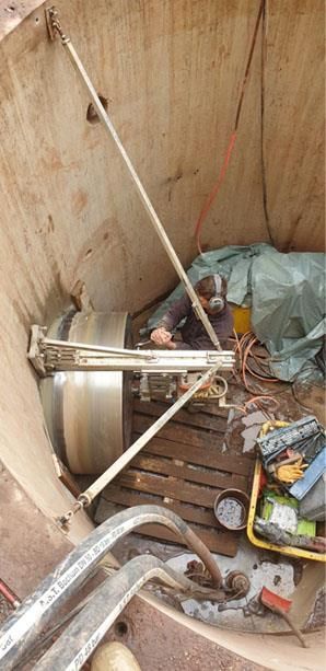 Ein Mann sitzt in einem Loch im Boden und arbeitet an einer Maschine.