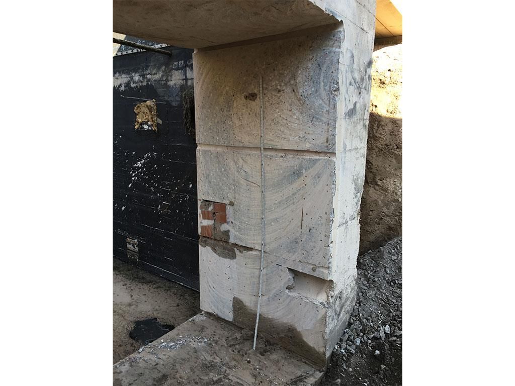 Eine Betonwand mit einer schwarzen Tür im Hintergrund