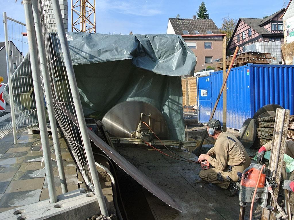 Ein Mann kniet vor einem großen Metallgegenstand