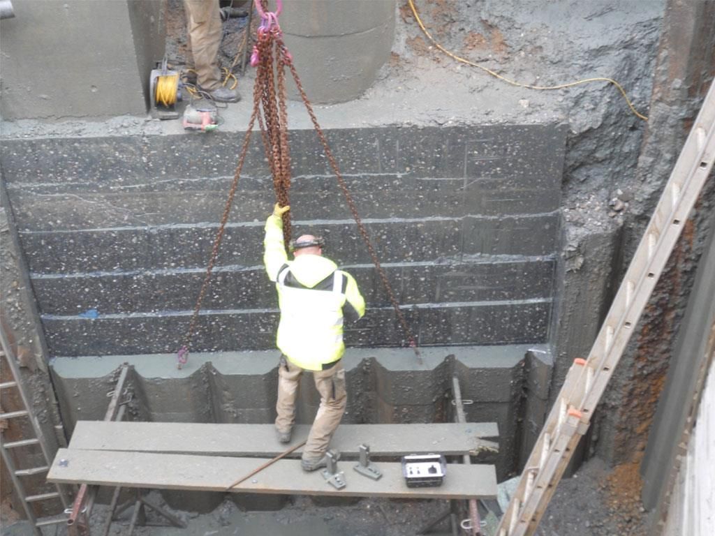 Ein Mann in einer gelben Jacke hebt etwas mit einer Kette hoch