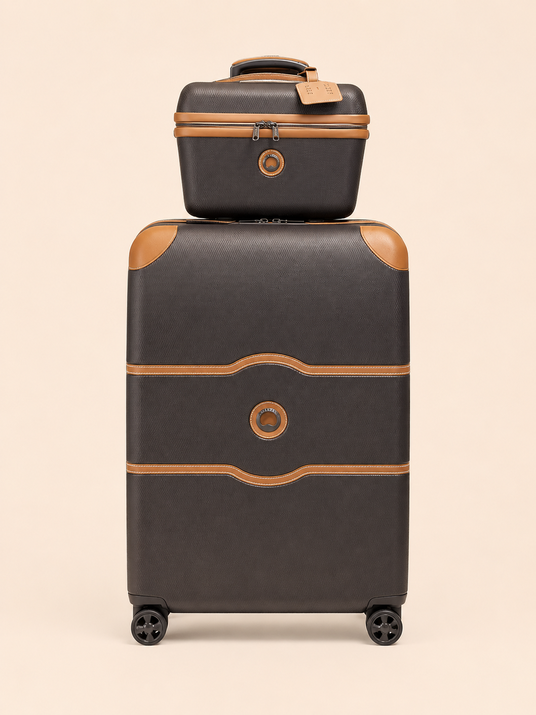 Valise rigide noire avec des accents beiges et petite valise assortie empilée dessus sur un fond beige.