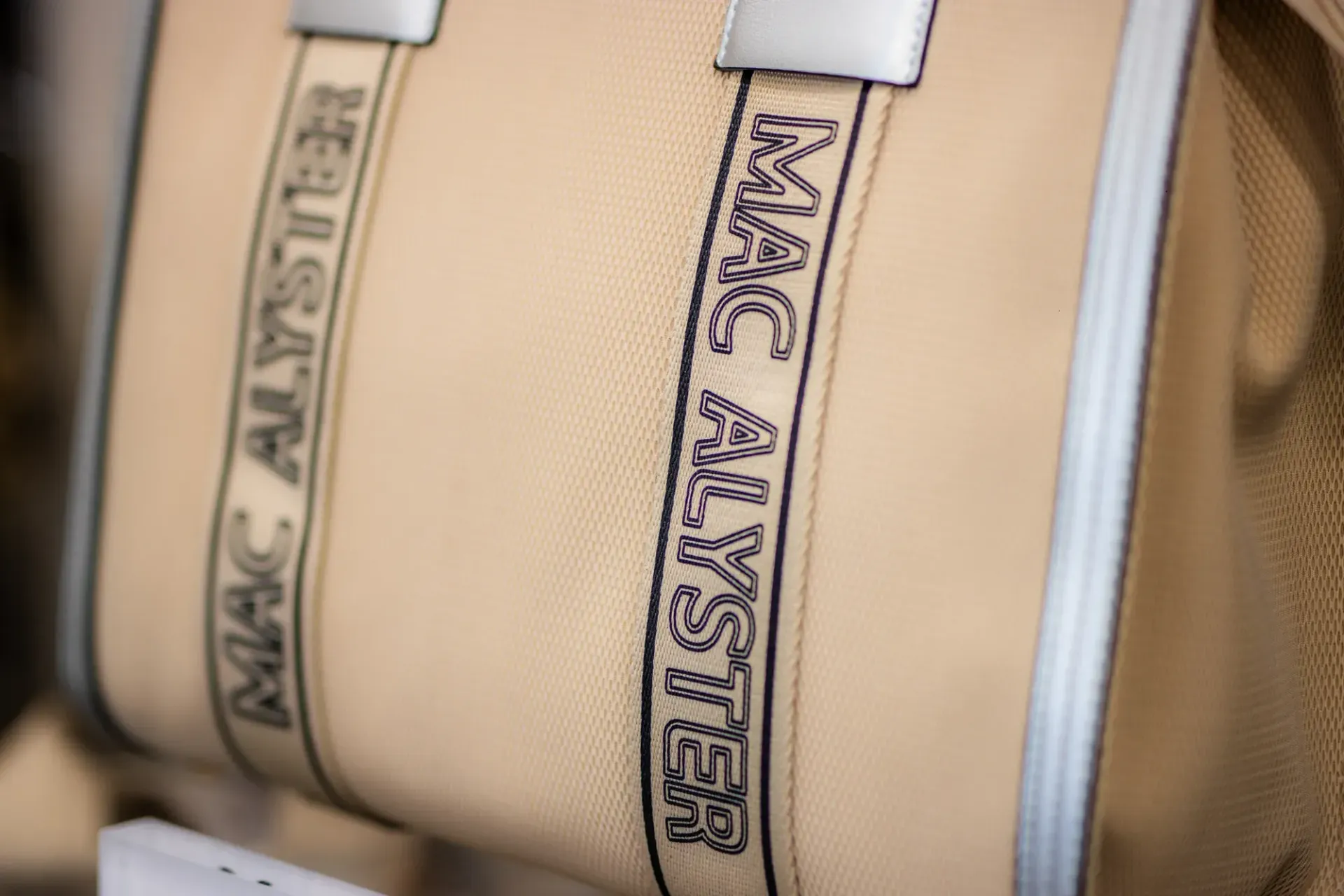 Gros plan sur un sac beige à anses argentées et inscription verticale MARC JACOBS.