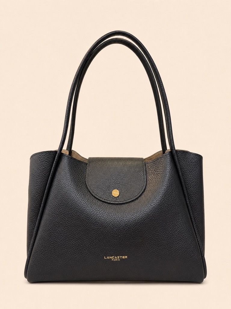 Une personne tenant un sac à main marron, assise sur une chaise blanche et vêtue de vêtements clairs.