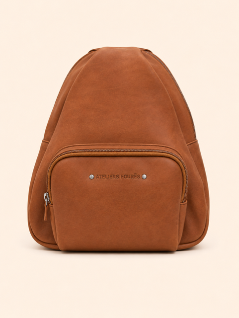 Sac à dos en cuir marron avec poche avant zippée sur fond beige uni