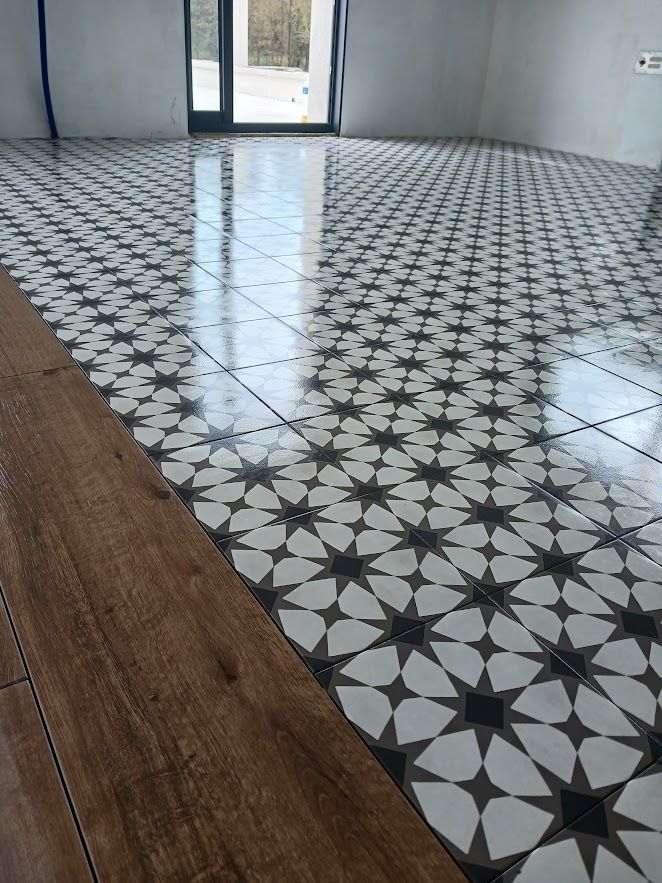 Sol carrelé à motifs décoratifs avec bordure en parquet. Pièce avec porte.