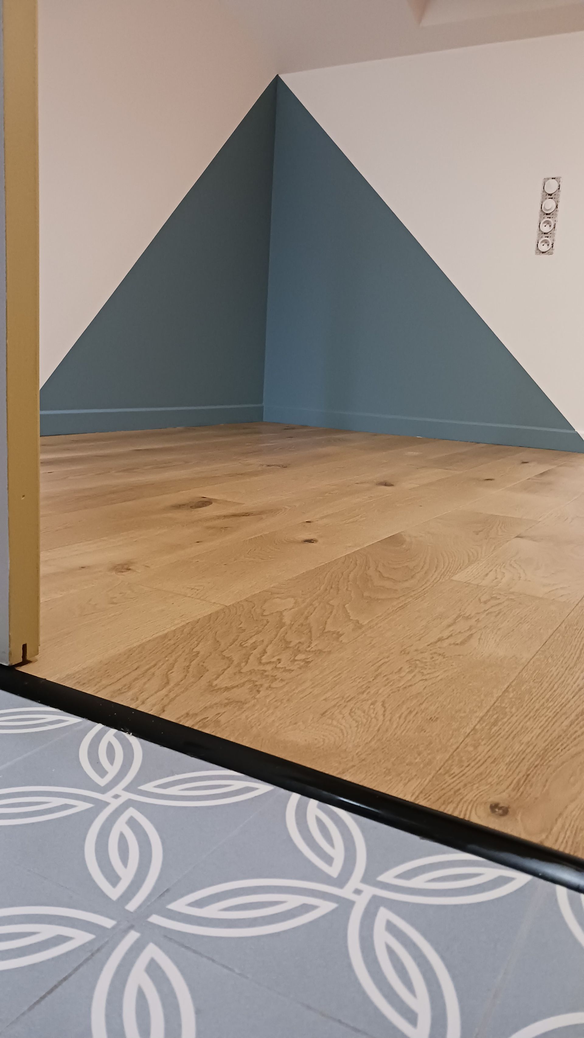 Sol en bois avec un mur d'accent bleu dans une pièce. Motif du sol au premier plan.
