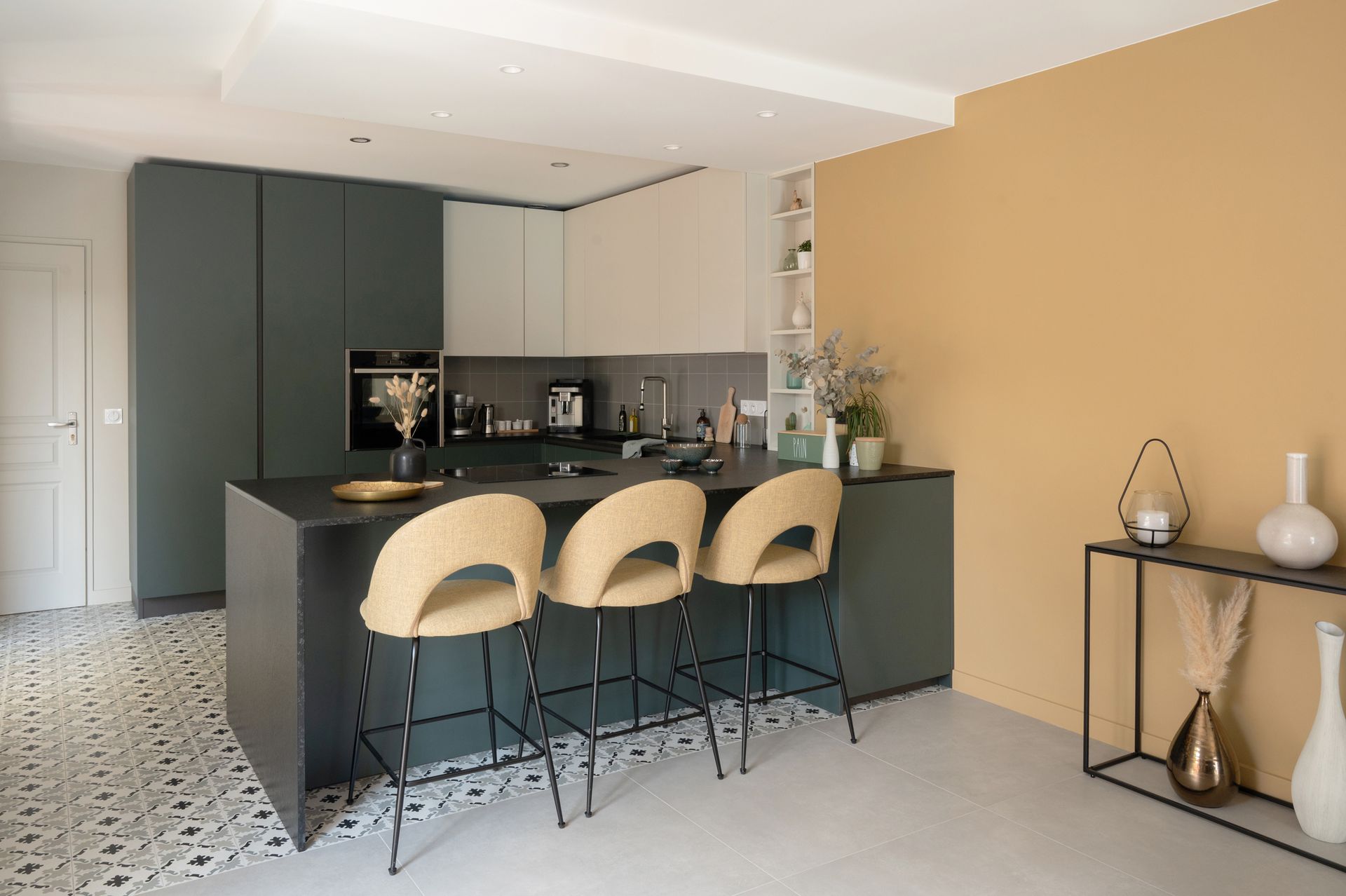 Cuisine moderne avec îlot central, tabourets de bar et murs jaunes.