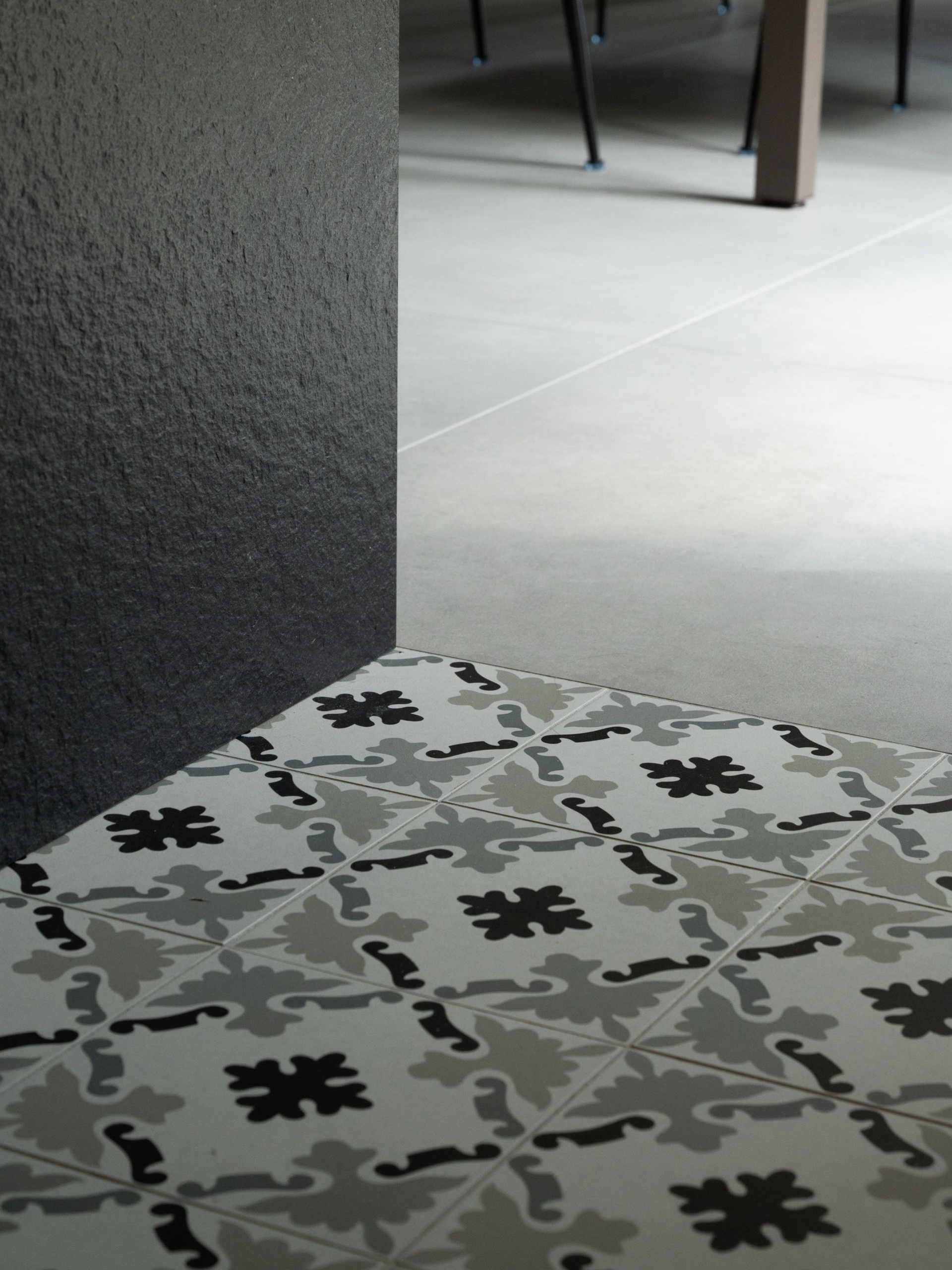 Carrelage à motifs gris et blancs à côté d'un mur texturé gris clair.