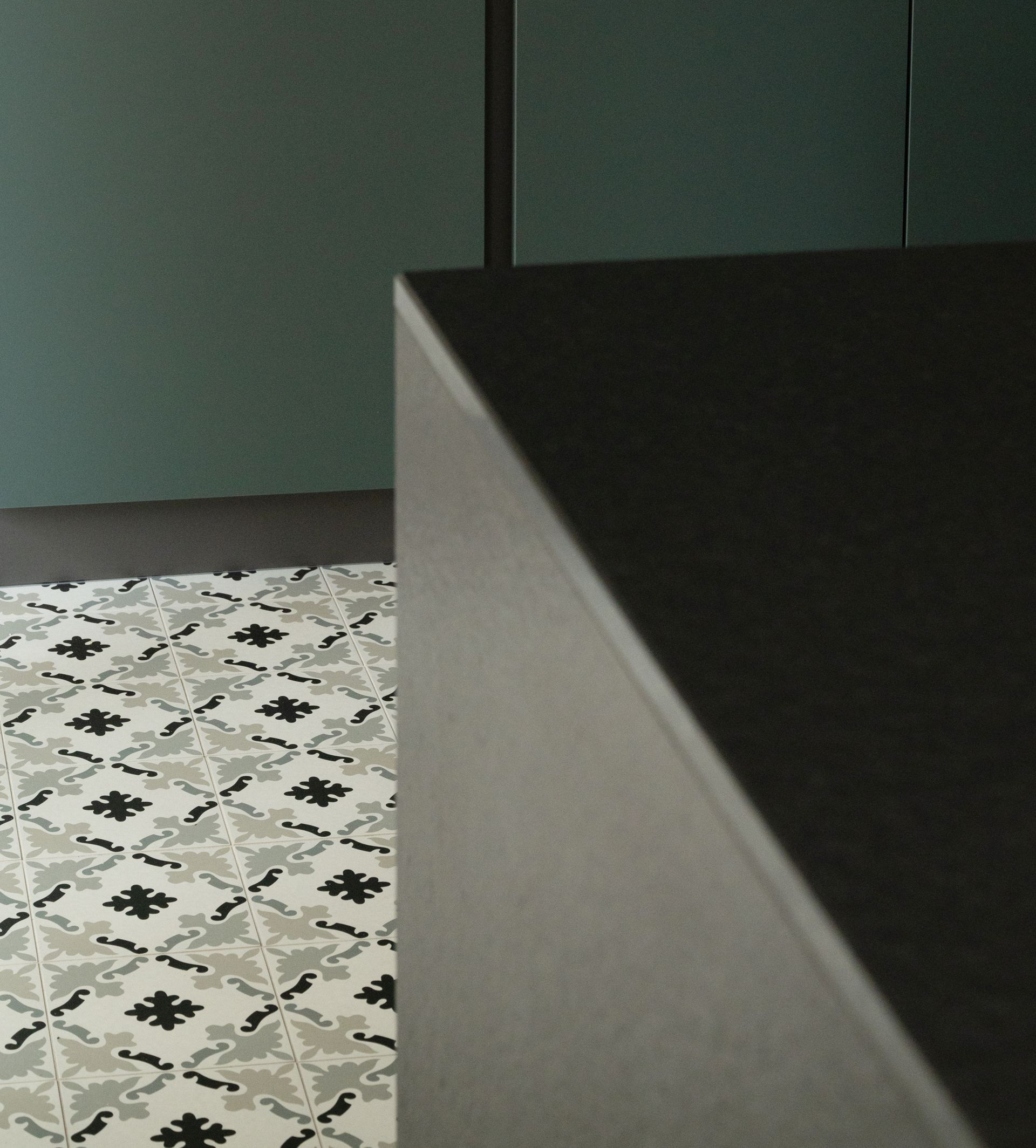 Coin d'un comptoir sombre, sol carrelé à motifs et mur bleu sarcelle foncé.