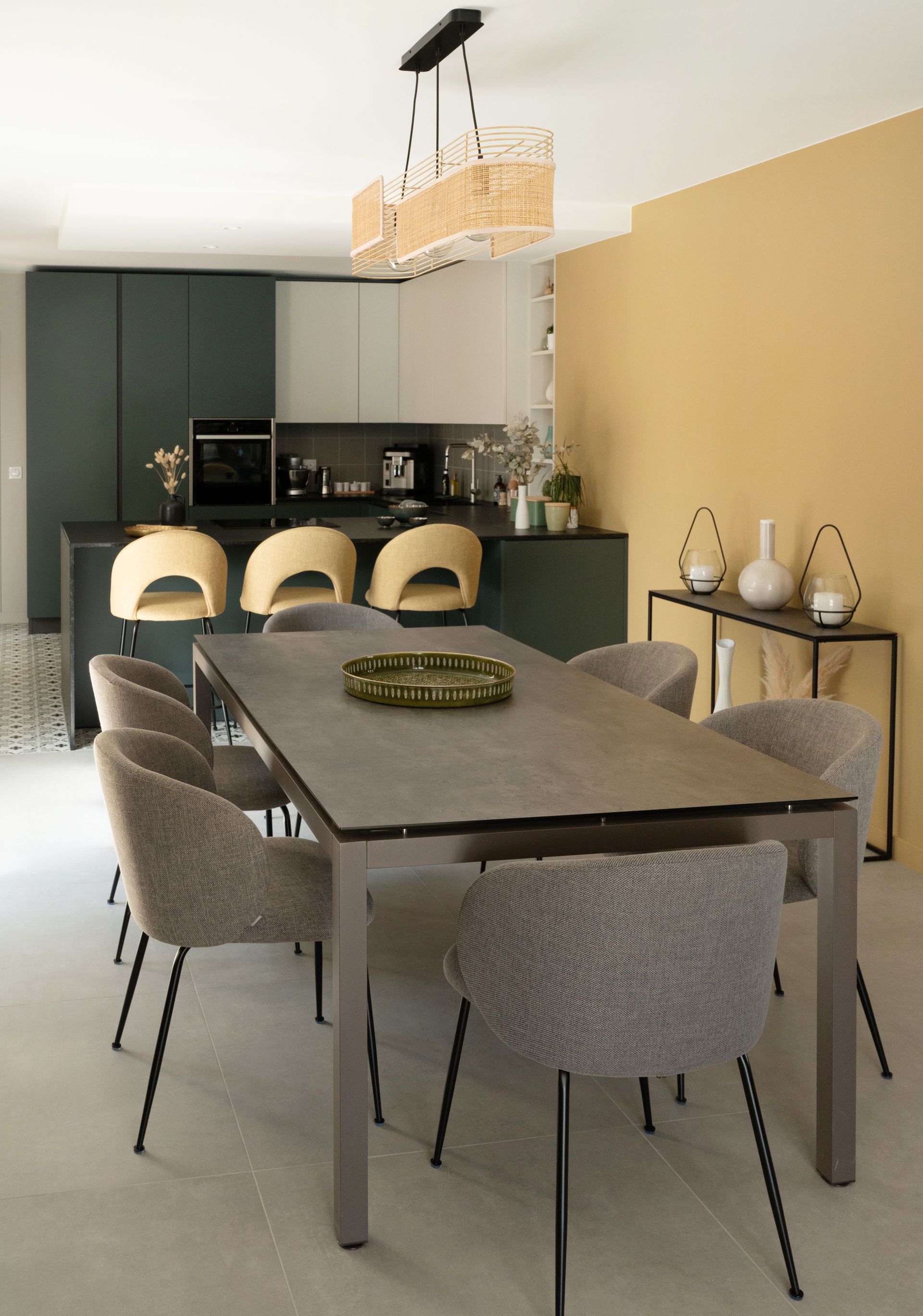 Salle à manger moderne avec table, chaises et îlot de cuisine avec tabourets de bar.