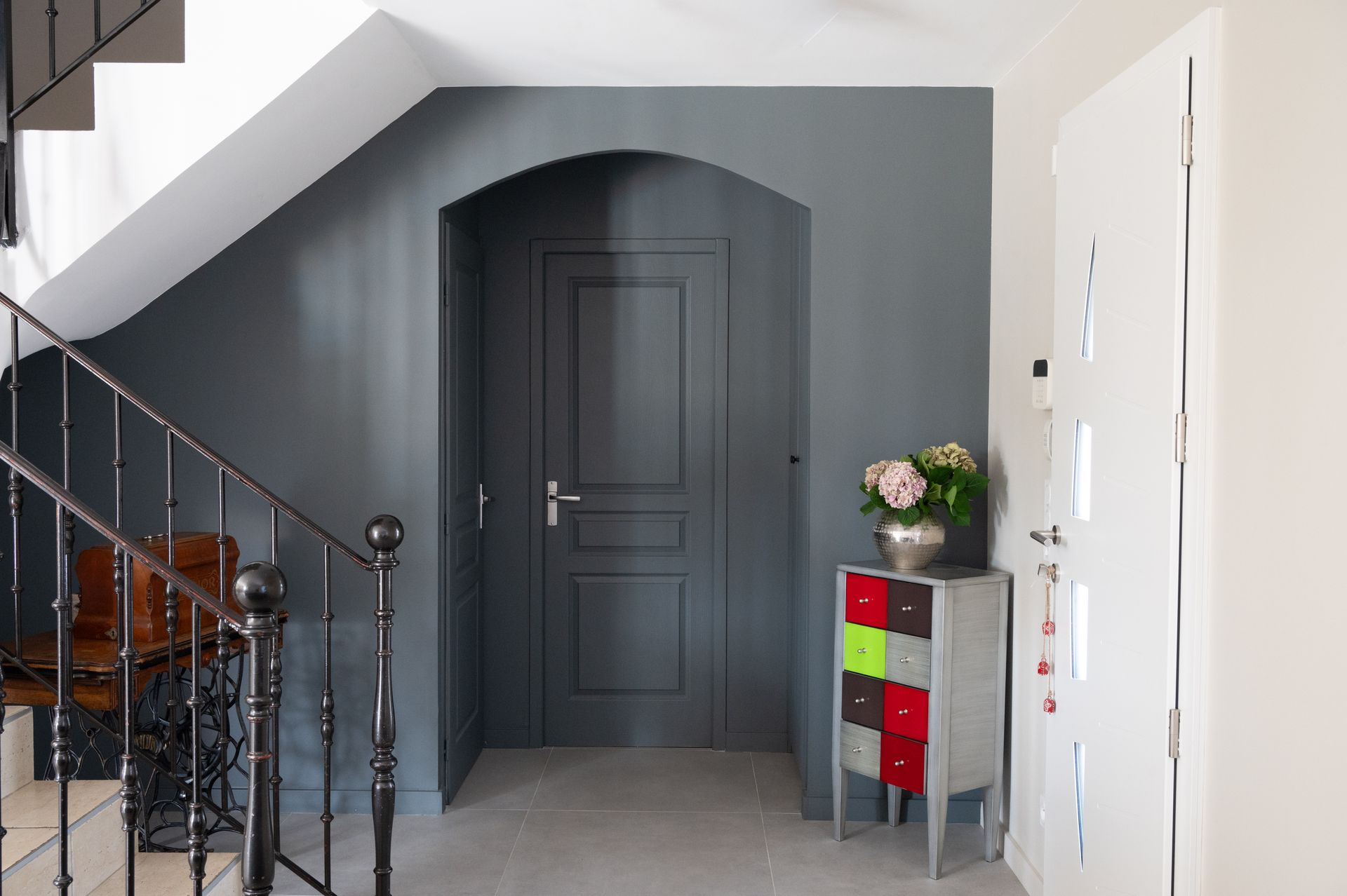 Entrée grise avec porte, escalier et armoire