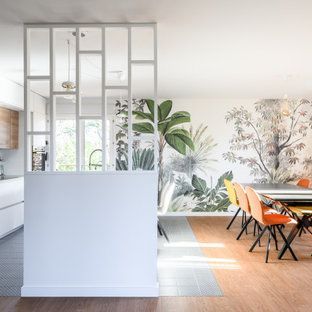 Salle à manger moderne avec cloison blanche, fresque tropicale et chaises colorées.
