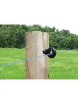 Un alambre azul de cerca eléctrica atraviesa un poste de madera en un campo de hierba.