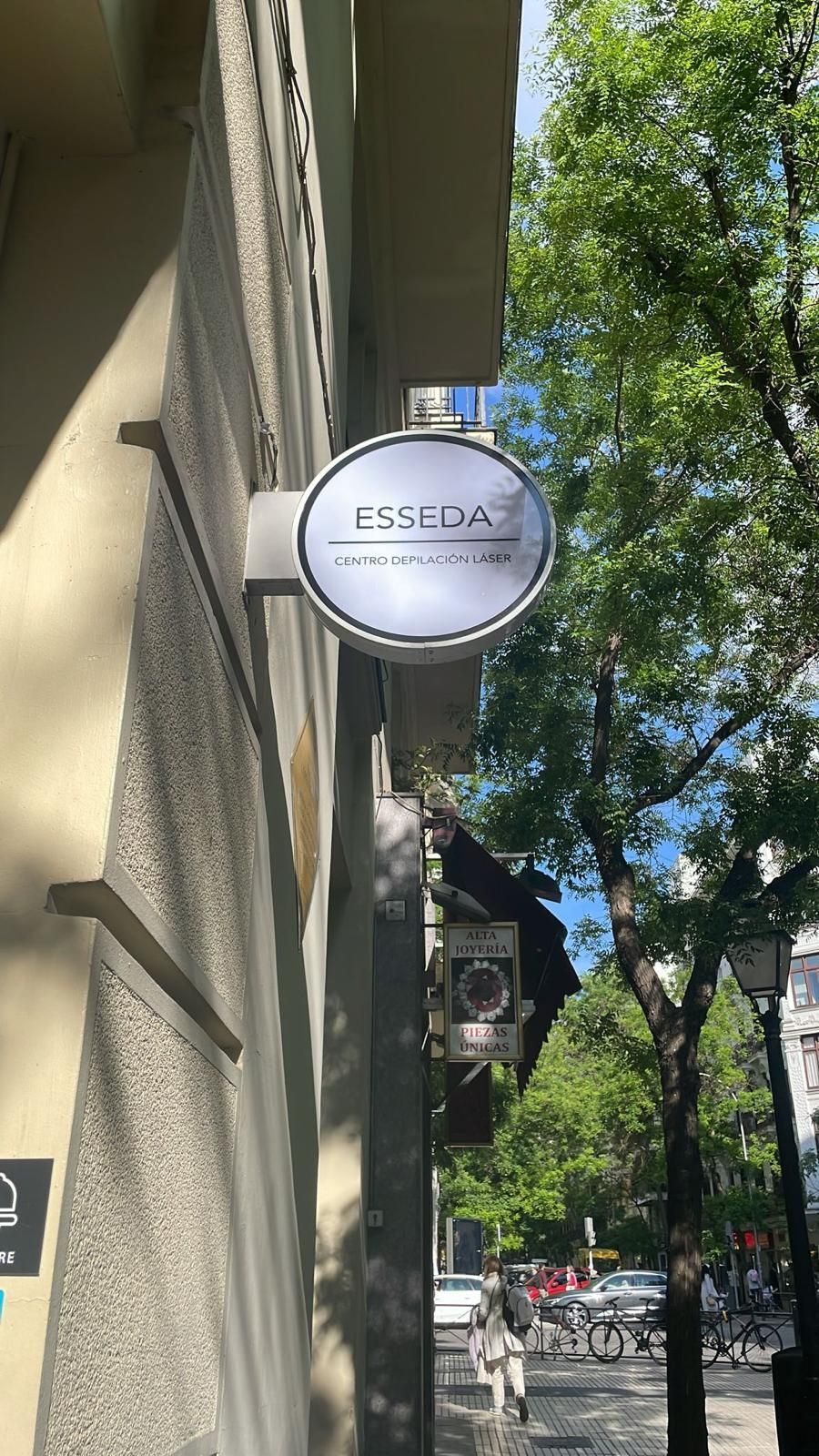 Letrero redondo de ESSO en la fachada de un edificio a lo largo de una calle arbolada.
