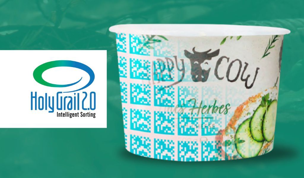 Happy Cow Joghurtbecher mit aufgedrucktem Code, Gurkenscheiben und Holy Grail 2.0-Logo.
