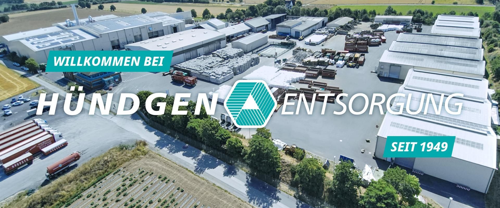 Luftaufnahme eines Industriegeländes mit dem Firmennamen „Hündgen Entsorgung“ in weißer Schrift, dem Firmenlogo und dem Text „seit 1949“.