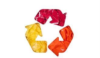 Recyclingsymbol aus rotem, orangefarbenem und gelbem Kunststoff. Drei Pfeile bilden die bekannte dreieckige Form.