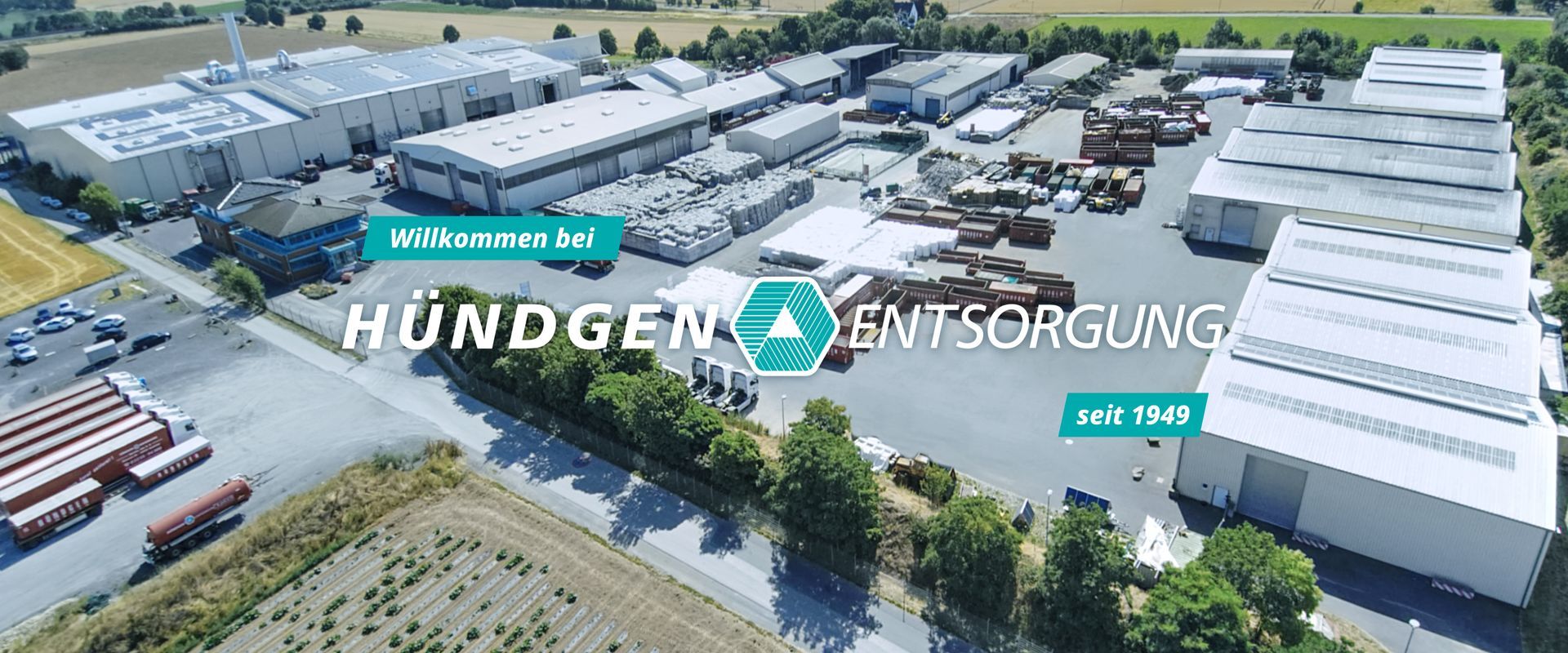Luftaufnahme des Betriebsgeländes der Firma „Hündgen Entsorgung“ in weißer Schrift, dem Firmenlogo und dem Text „seit 1949“.