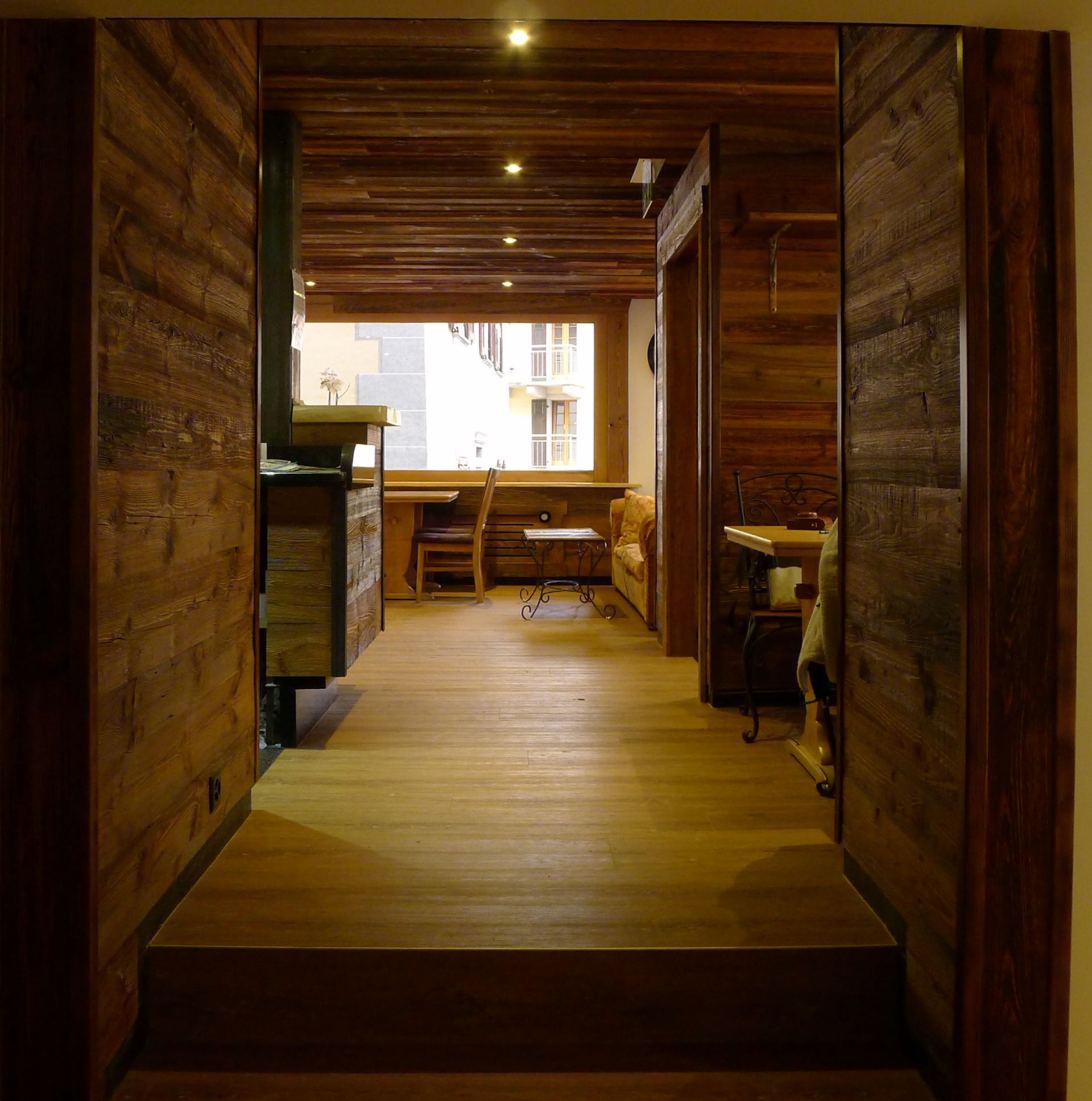 Un couloir avec des murs et du parquet en bois menant à un salon