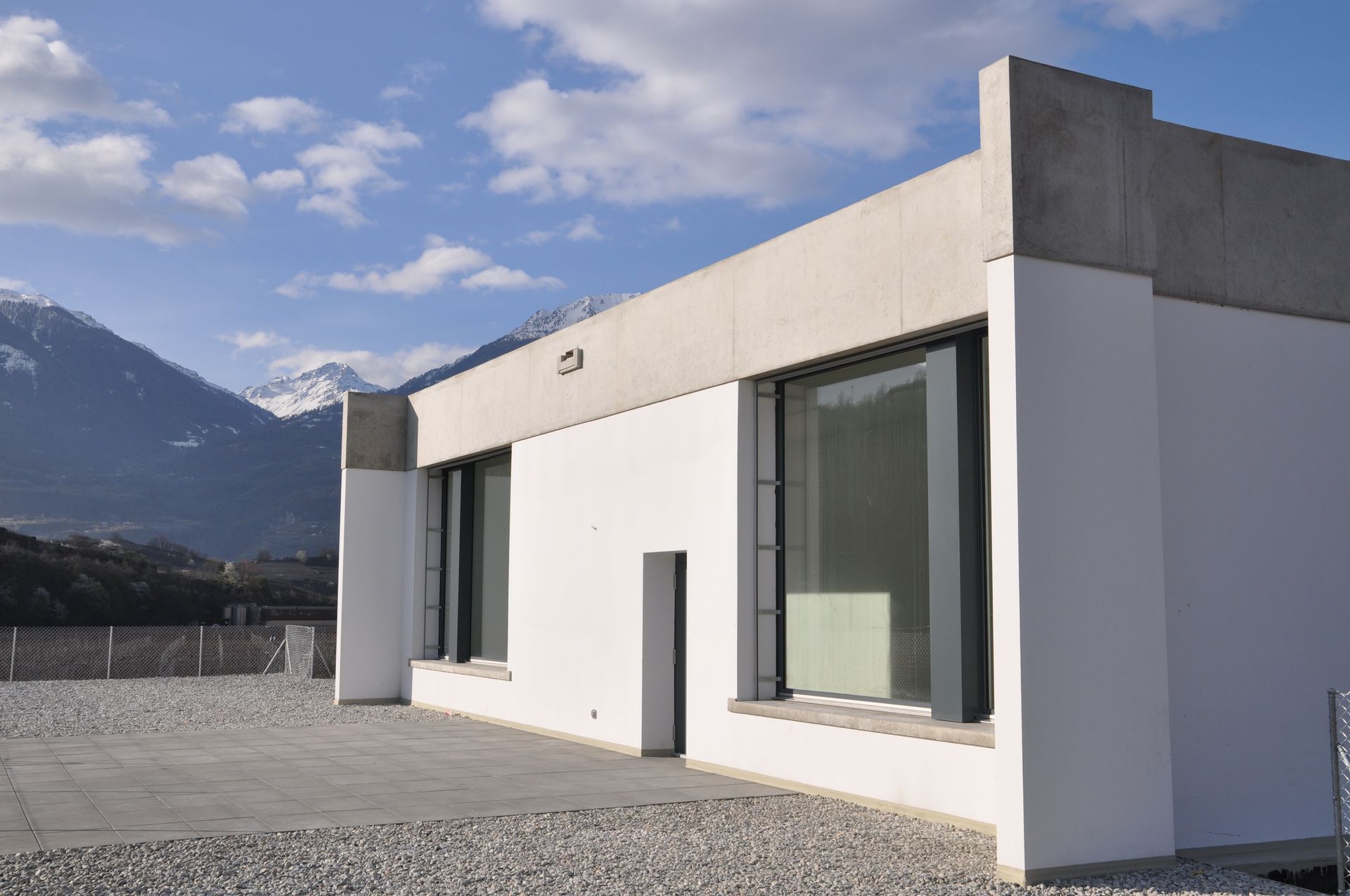 Un bâtiment blanc avec beaucoup de fenêtres et des montagnes en arrière-plan