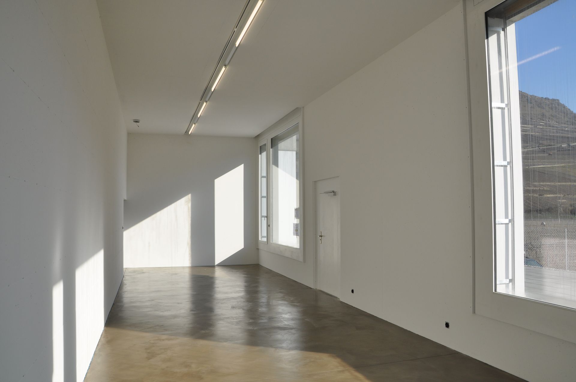 Une grande pièce vide avec des murs blancs et un plancher en bois.